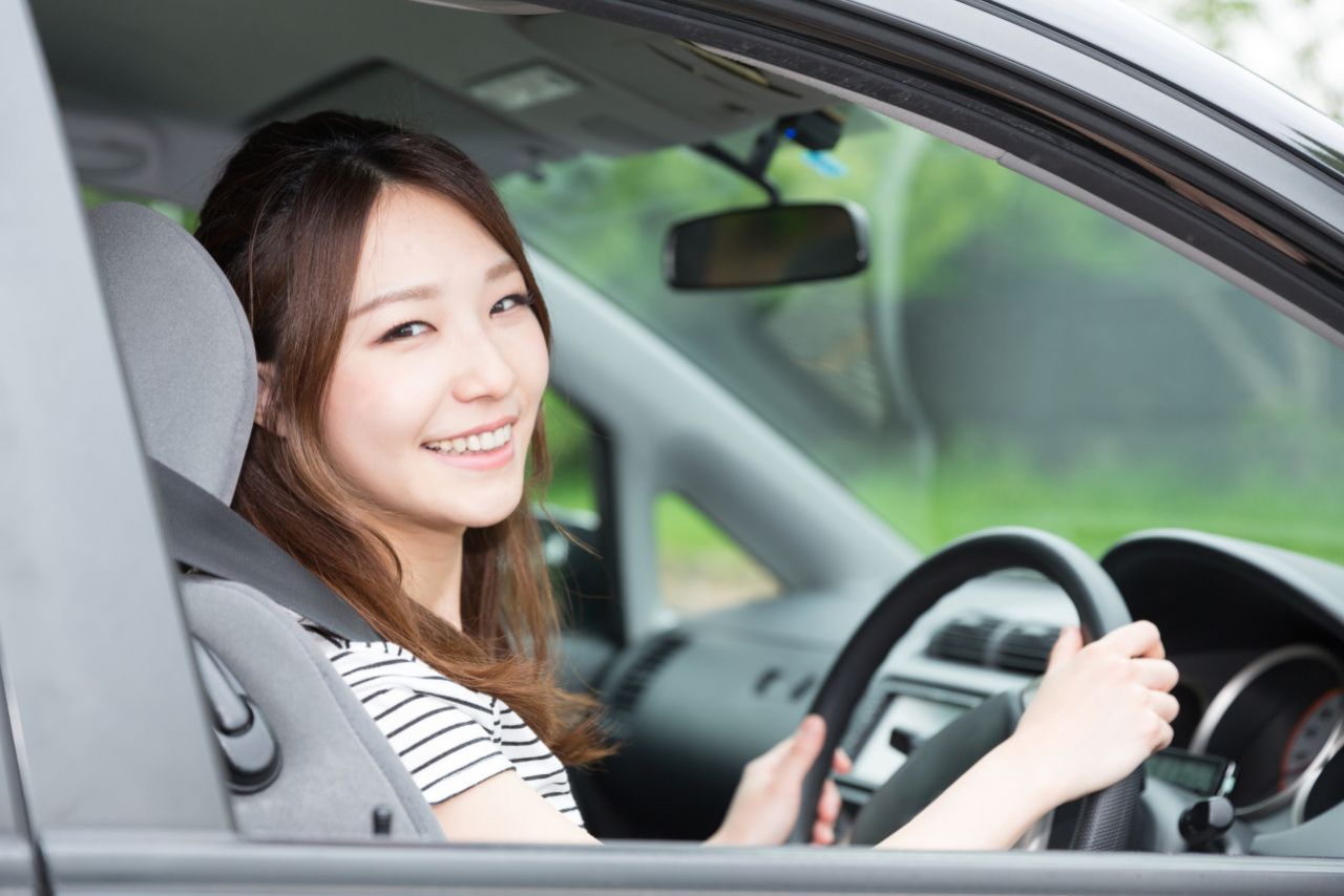 運転席に座りながら微笑む女性